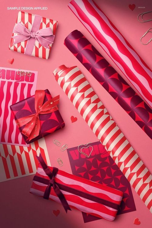 Valentine’s wrapping paper mockup featuring rolled sheets and wrapped gifts in red and pink geometric patterns, top view.