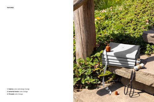 PSD mockup showing a pile of patterned fabrics on outdoor stone steps, with plants and sewing accessories in view.