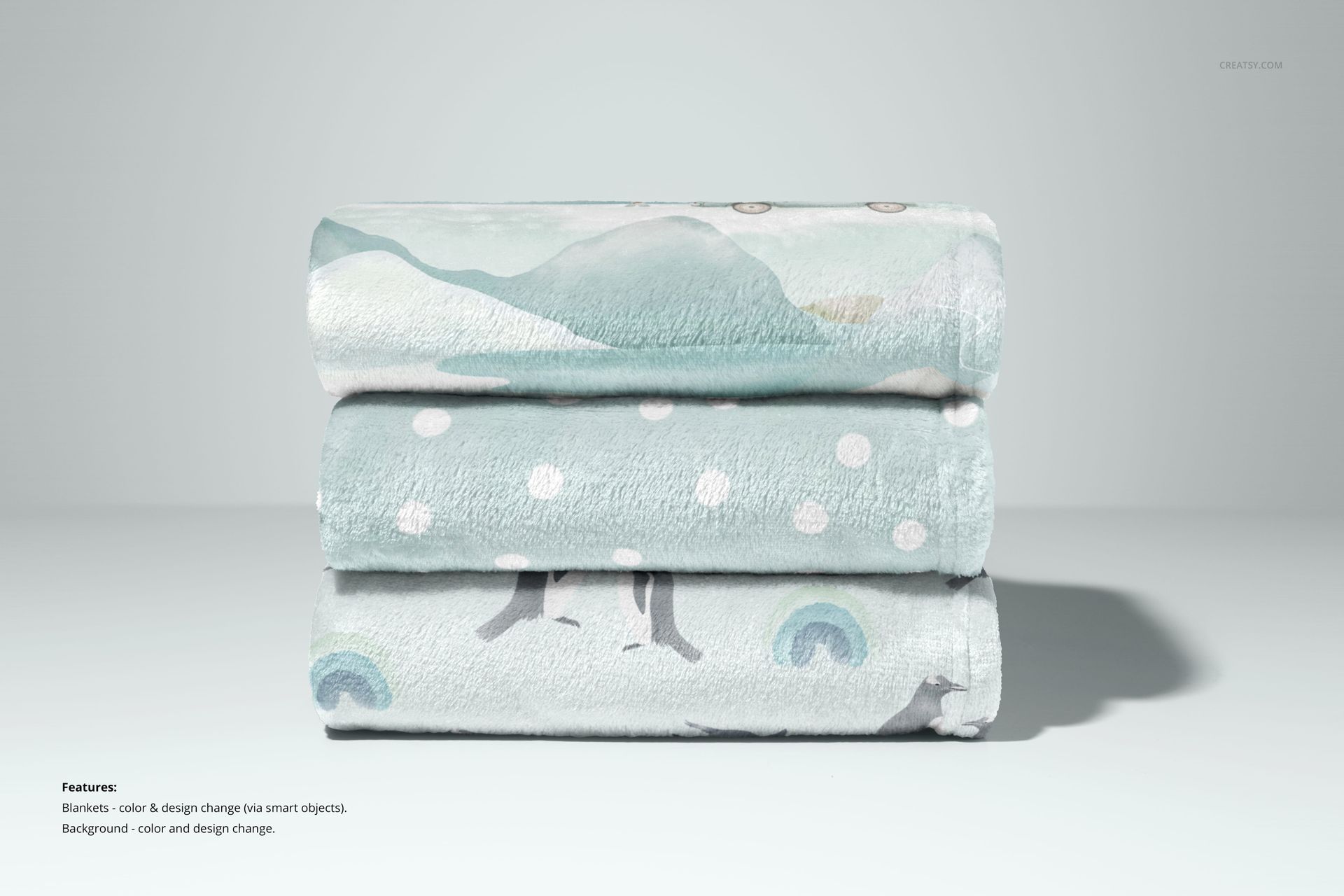 PSD mockup of stacked fleece blankets in light blue and gray, each with different playful patterns, studio background.