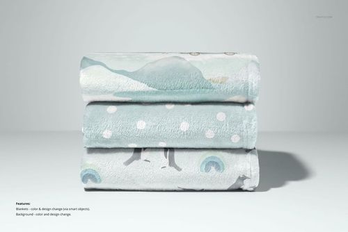 PSD mockup of stacked fleece blankets in light blue and gray, each with different playful patterns, studio background.