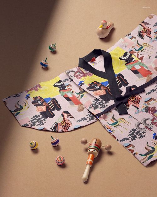 Kids yukata mockup with colorful animal and nature patterns, displayed on a beige surface with wooden toys.