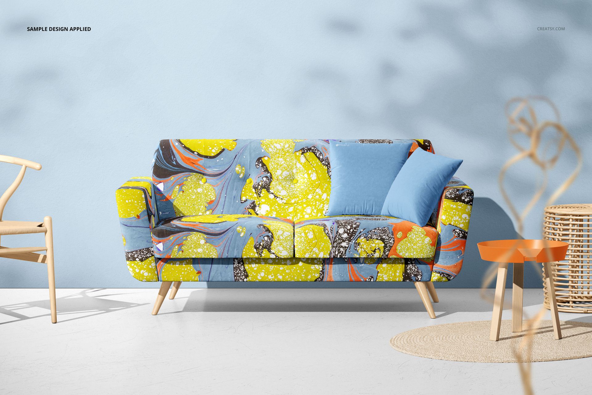 Front-facing sofa mockup featuring bold yellow and blue abstract patterns and two solid blue accent pillows.