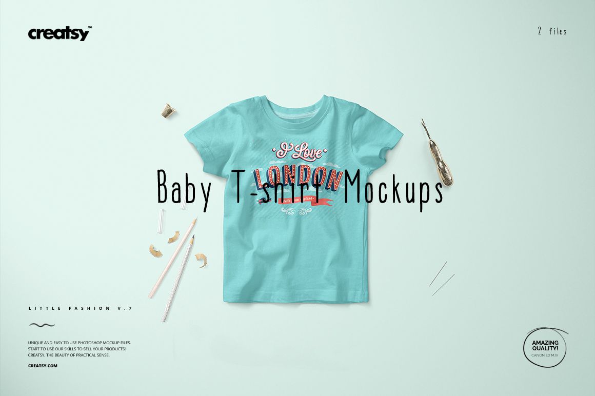 Front view of a light blue baby T-shirt mockup displayed on a pale surface with scattered art supplies around.