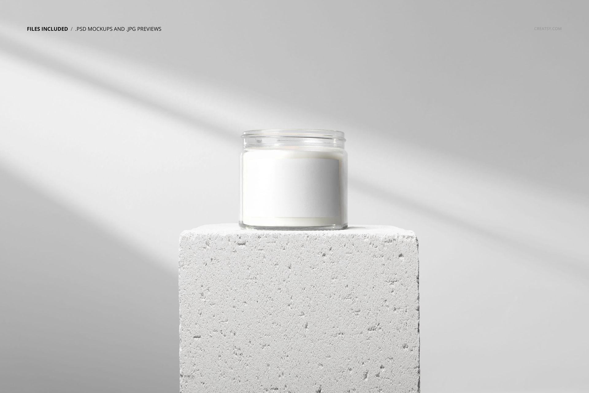 Minimalist clear glass candle jar mockup shown on a white stone pedestal, featuring a blank label and neutral background.