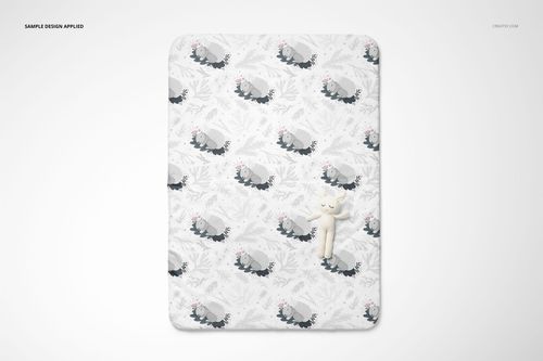 Top view of a double-sided baby bedding set mockup featuring a quilt with animal pattern and a plush toy on white background.