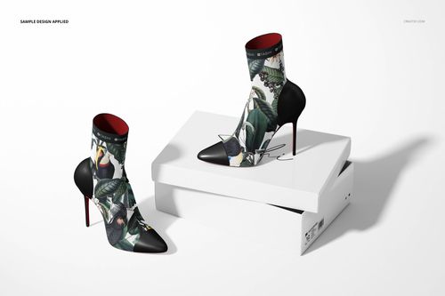 Mockup of ankle boots featuring a vibrant jungle design, black stiletto heels, and red interiors, arranged with a white shoebox.