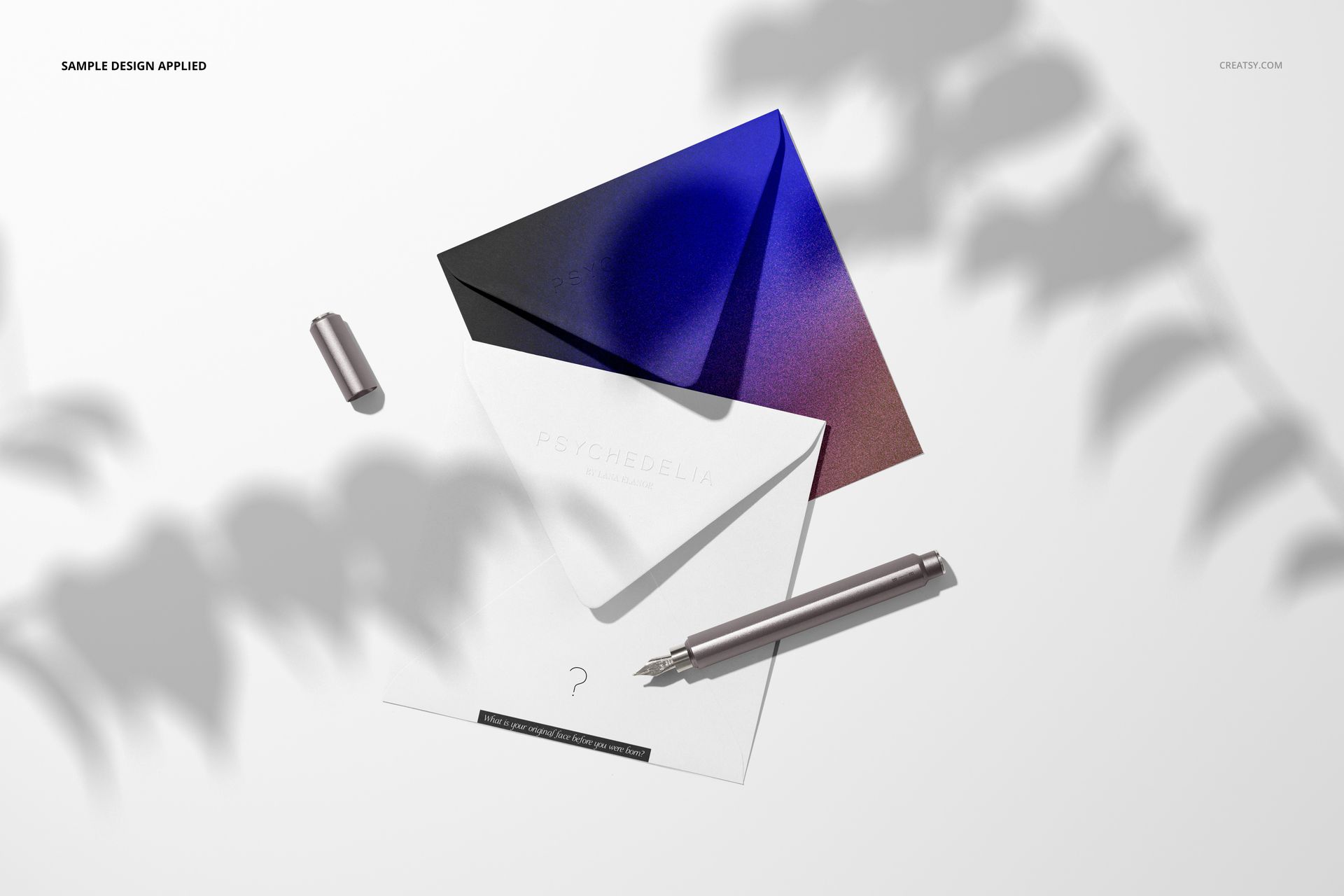 Square stationery card and envelope mockup set with gradient envelope, white card, and metallic pen on a light surface.