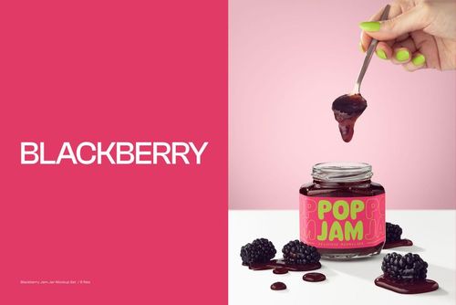 PSD mockup showing a glass jam jar with colorful label, fresh blackberries, and a hand holding a spoon with jam.