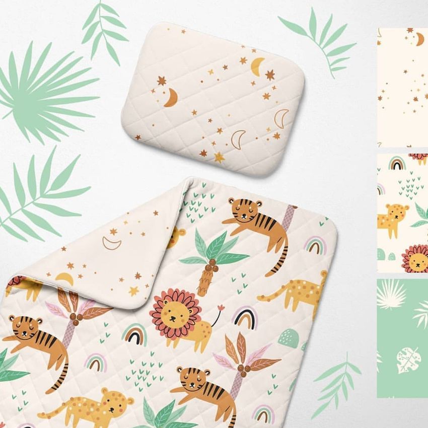 Double-sided baby bedding set mockup featuring a quilt and pillow with playful safari animal illustrations and leaf accents on a light background.