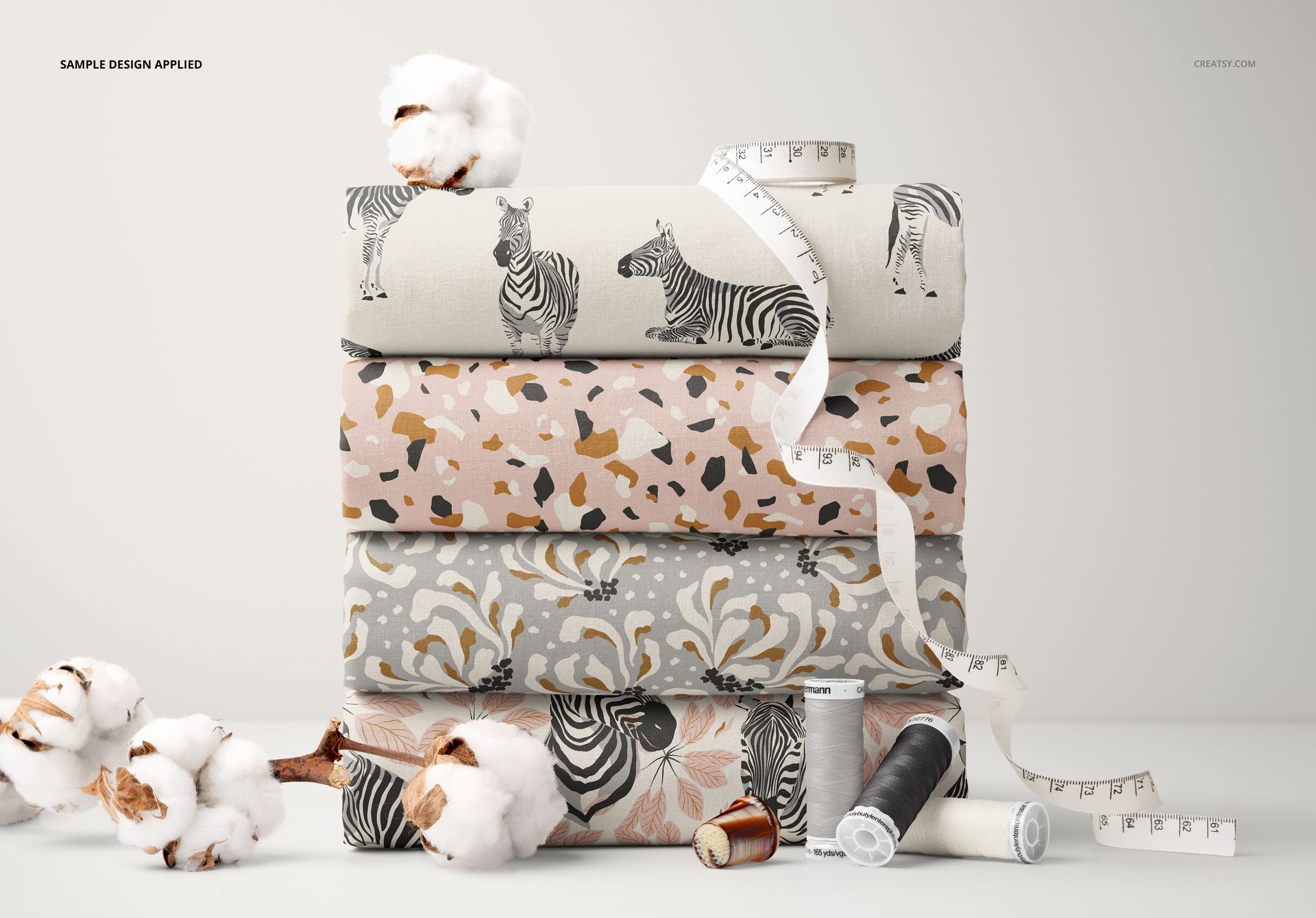Cotton fabric mockup featuring four patterned fabrics stacked together, displayed with sewing accessories and cotton flowers.