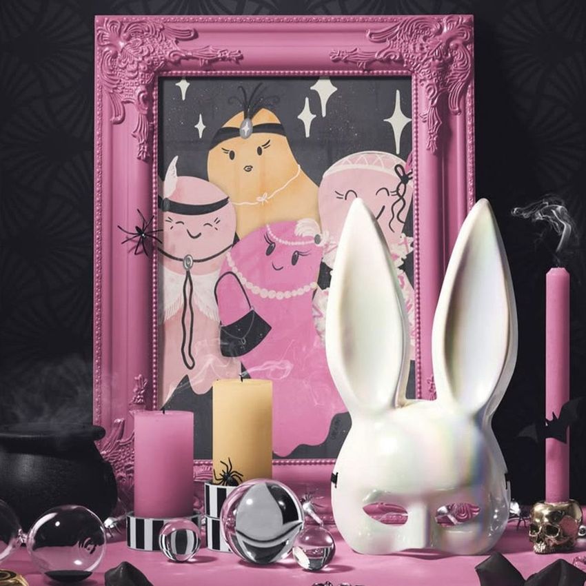 Halloween art print mockup featuring a pink ornate picture frame with illustrated characters, surrounded by candles and props.