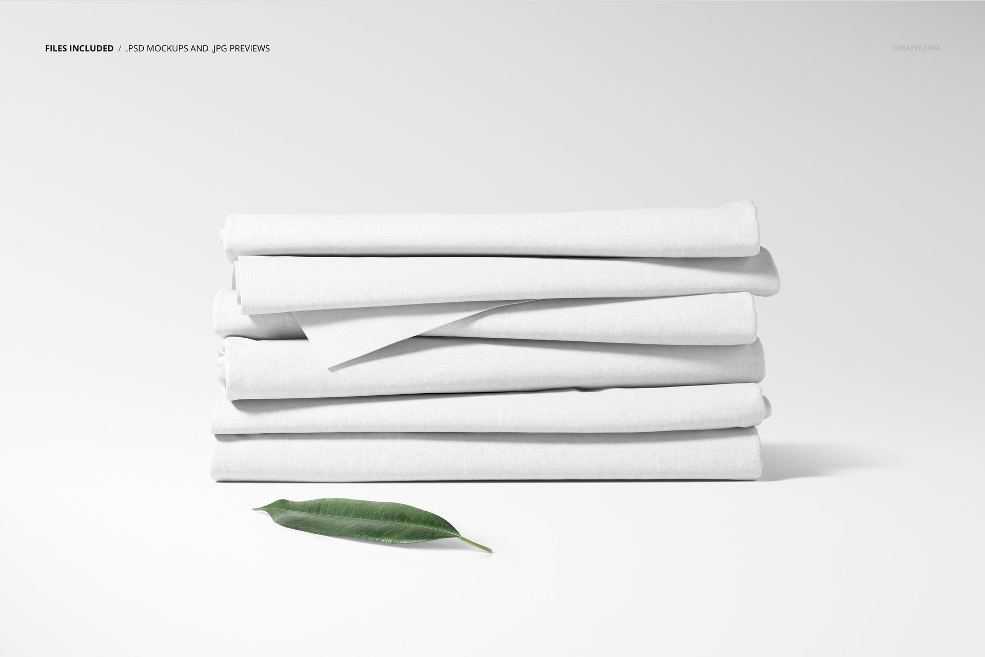 Fabric stack mockup featuring five folded white textiles in a horizontal arrangement, with a green leaf placed below.