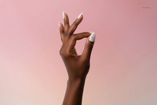 Hand with manicured nails featuring a light pastel design, shown against a soft pink gradient background, front view.