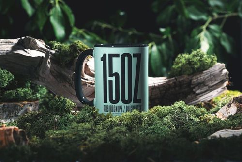 Nature scene PSD mockup featuring a large mug with dark handle, set among moss, wood, and leafy greenery.
