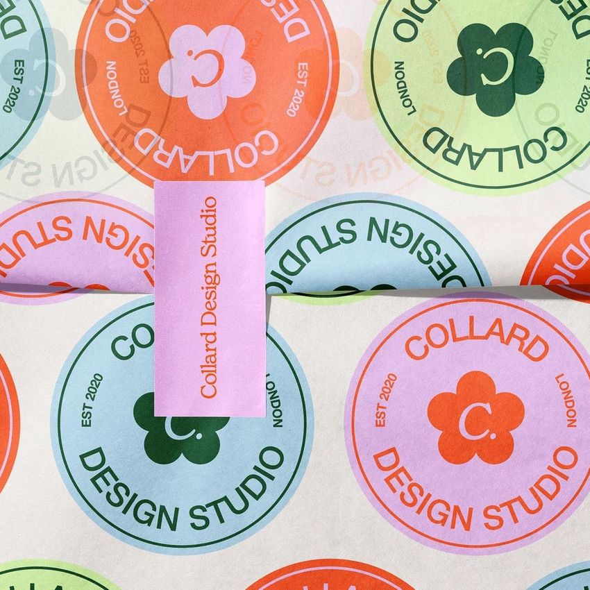 Wrapping paper mockup featuring colorful circular patterns with text and a pink sticker placed on top, viewed from above.