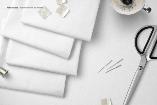 White textile mockup featuring folded fabric layers, metal scissors, sewing pins, buttons, and a coffee cup.