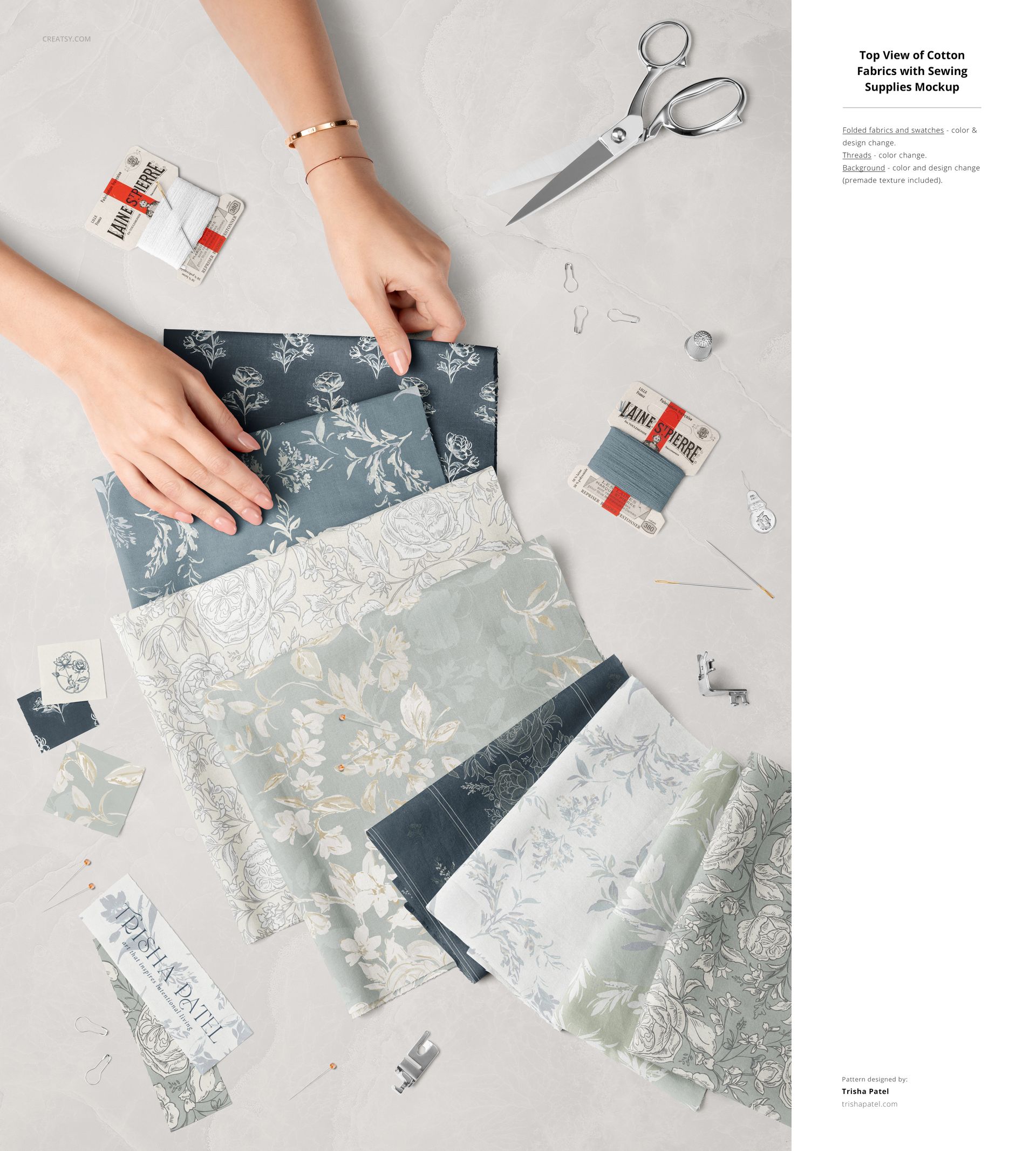 Top view of cotton fabric pieces with floral patterns in blue and gray tones, surrounded by sewing tools and hands.