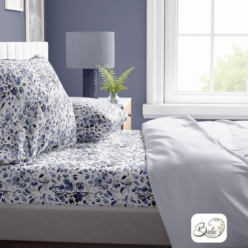 Brushed cotton sheet mockup featuring a bed with blue and white floral patterned sheets, a lamp, and a plant on a nightstand.