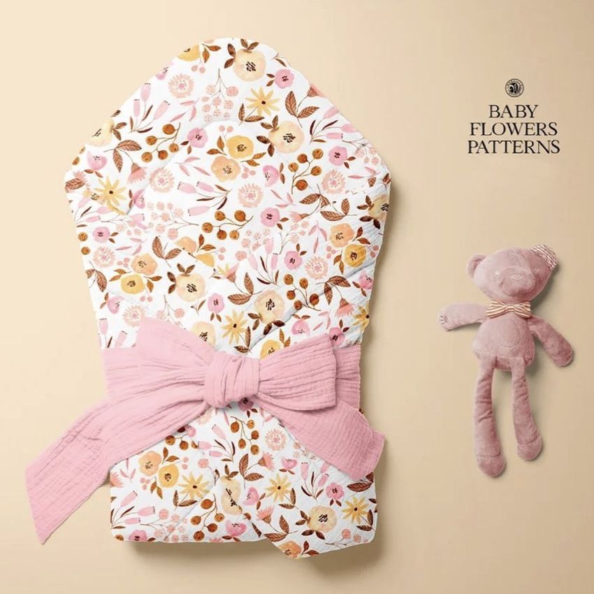 Muslin baby wrap mockup with a pink and brown floral pattern, tied with a pink fabric bow, next to a plush pink teddy bear on a beige background.