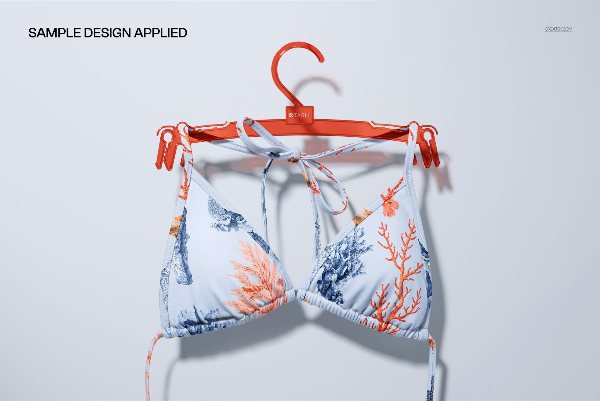 Front view of a triangle bikini top mockup featuring ocean-inspired coral print, displayed on a red hanger.