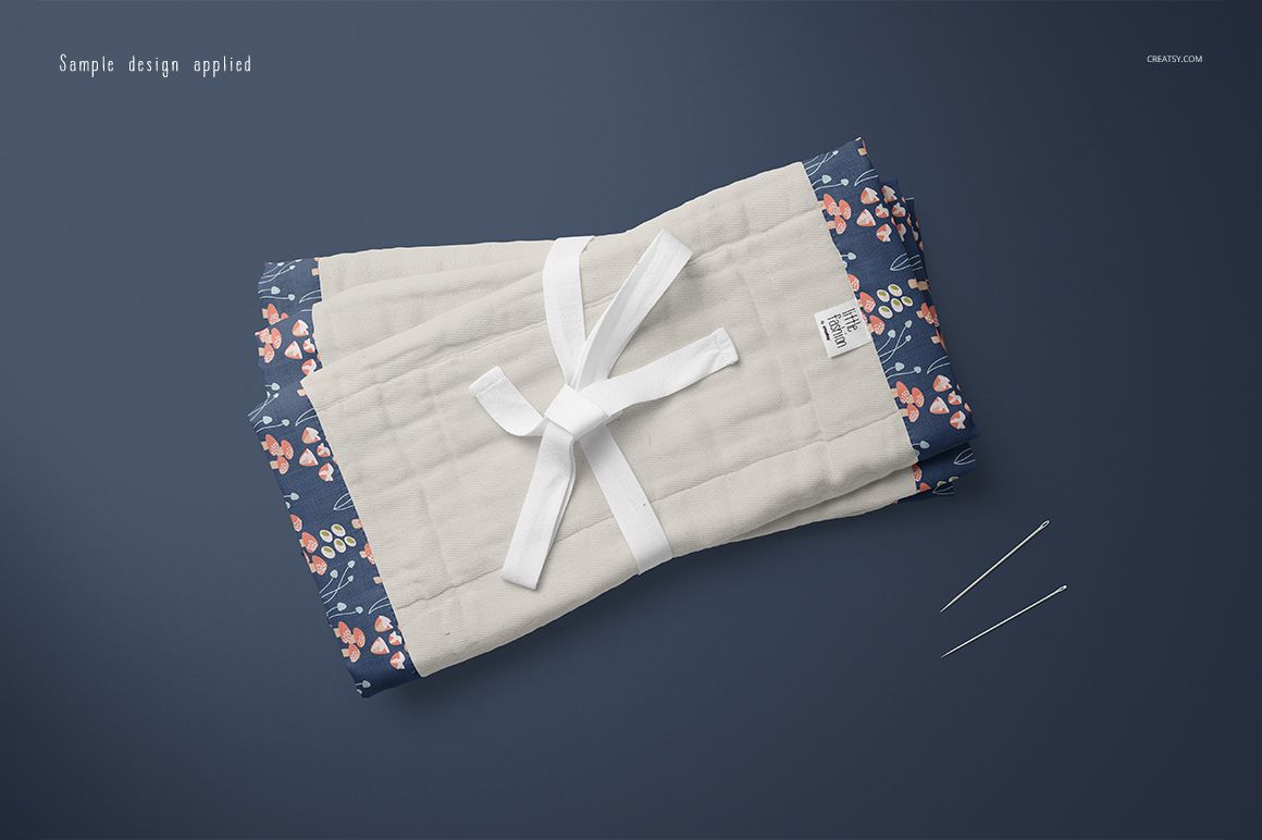 Burp cloth mockup showing a folded fabric with white middle section and floral borders, viewed from above.