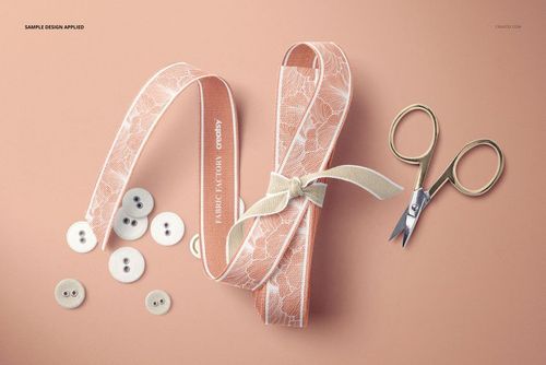 Cotton ribbon with lace design, small scissors, and white buttons arranged on a soft peach surface, PSD mockup.