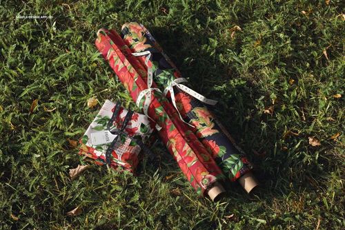 PSD mockup showing colorful fabric rolls and a folded bundle with ribbon, arranged on natural meadow grass.