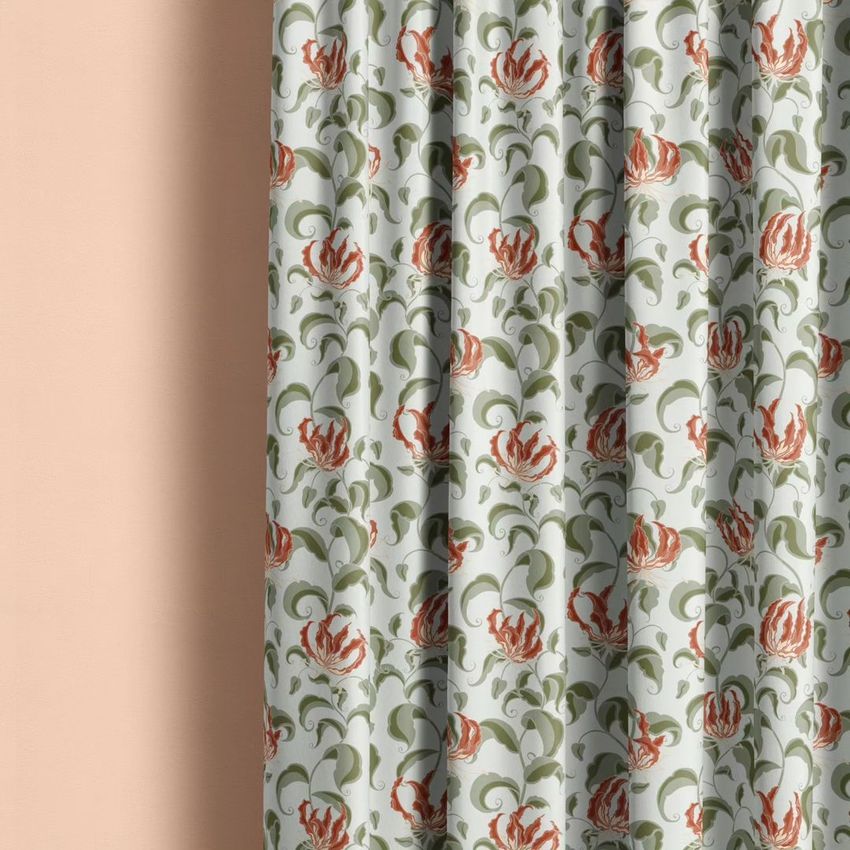 Curtain mockup showing a closeup of fabric with a floral pattern in red, green, and cream against a soft peach wall.