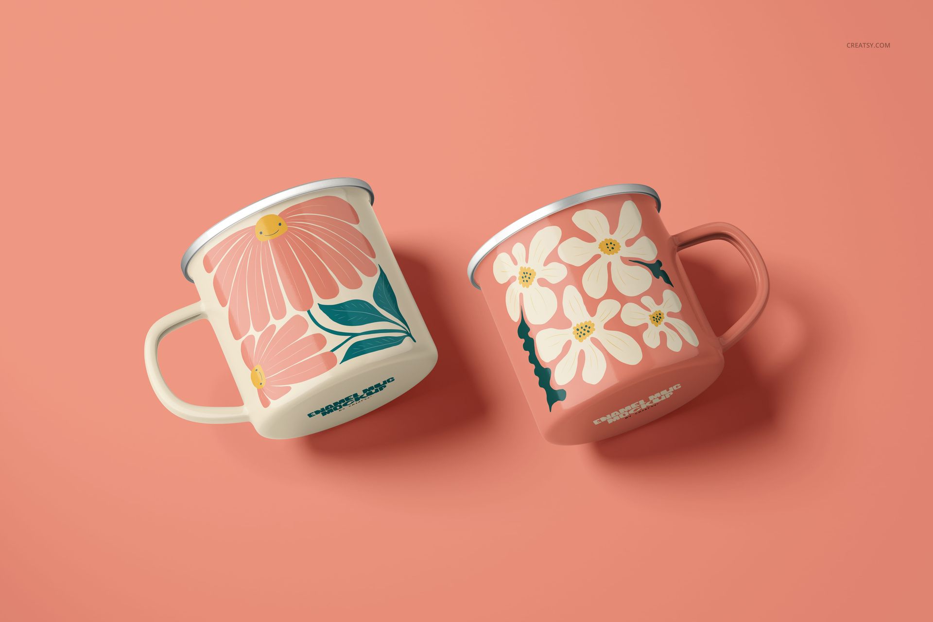 PSD mockup set showing a pair of enamel mugs with silver rims and vibrant floral artwork on a solid peach surface.