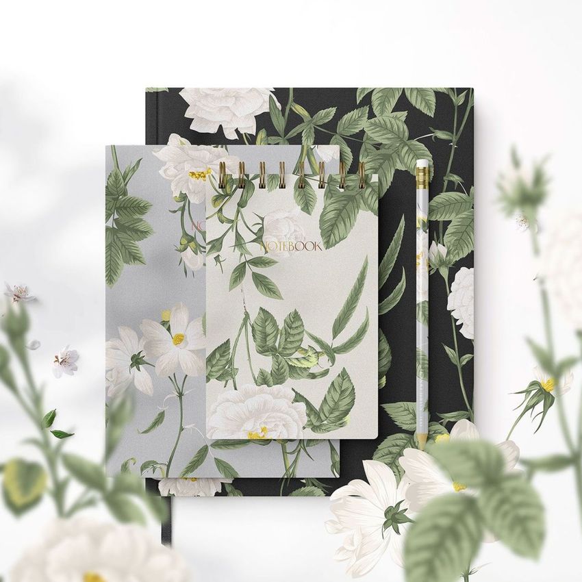Stationery set mockup featuring a spiral notebook, hardcover notebook, and pencil with green floral patterns on a white background.