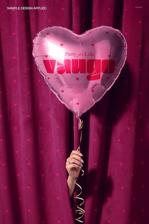 PSD mockup showing a person holding a heart-shaped party balloon with a velvet curtain background decorated with tiny hearts.
