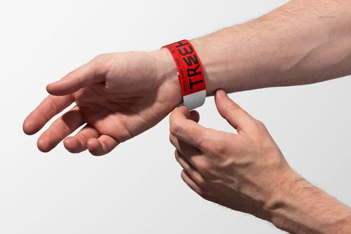 Front view of a paper wristband mockup in red and white, displayed on a human wrist with neutral background.