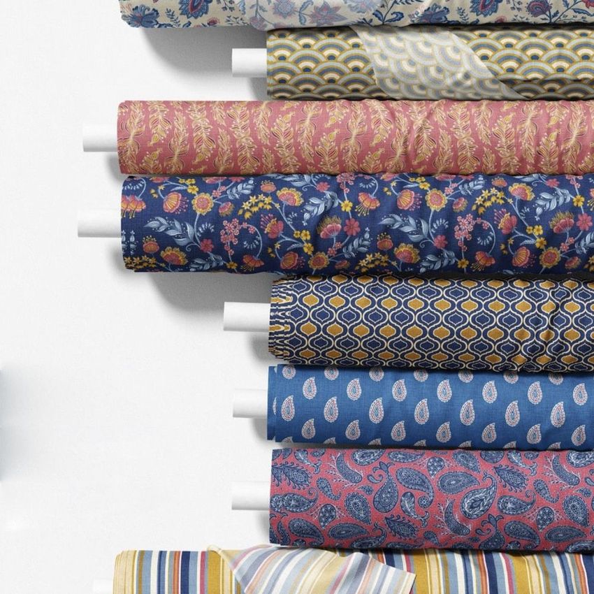 Fabric rolls mockup featuring nine rolls with various colorful patterns, including florals, paisleys, and geometric designs on a white background.