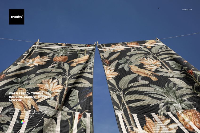 PSD mockup showing two decorative waffle beach towels with tropical motifs hanging side by side against the sky.
