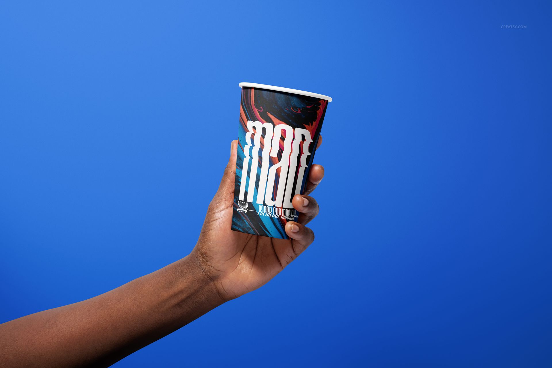 Hand holding a paper cup with bold graphic design against a solid blue background, front view mockup scene.