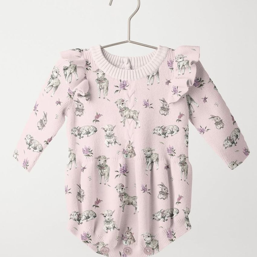 Hanging knitted romper mockup featuring a pale pink baby romper with illustrated lamb and bunny pattern on a plain background.