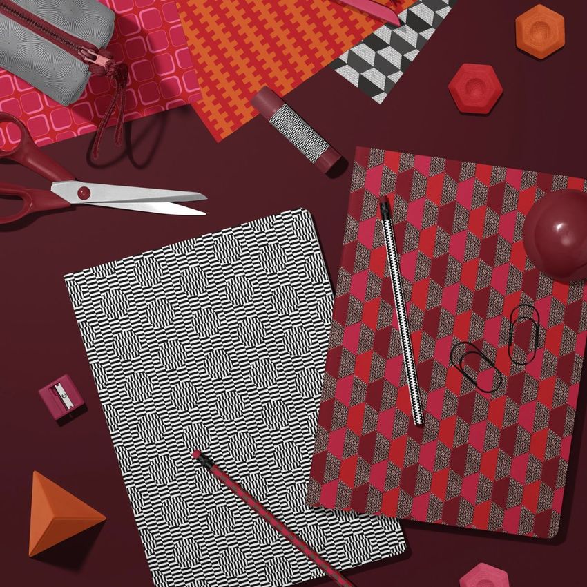Stationery mockup featuring two classic A4 notebooks with bold geometric patterns, surrounded by red and black office supplies on a dark surface.