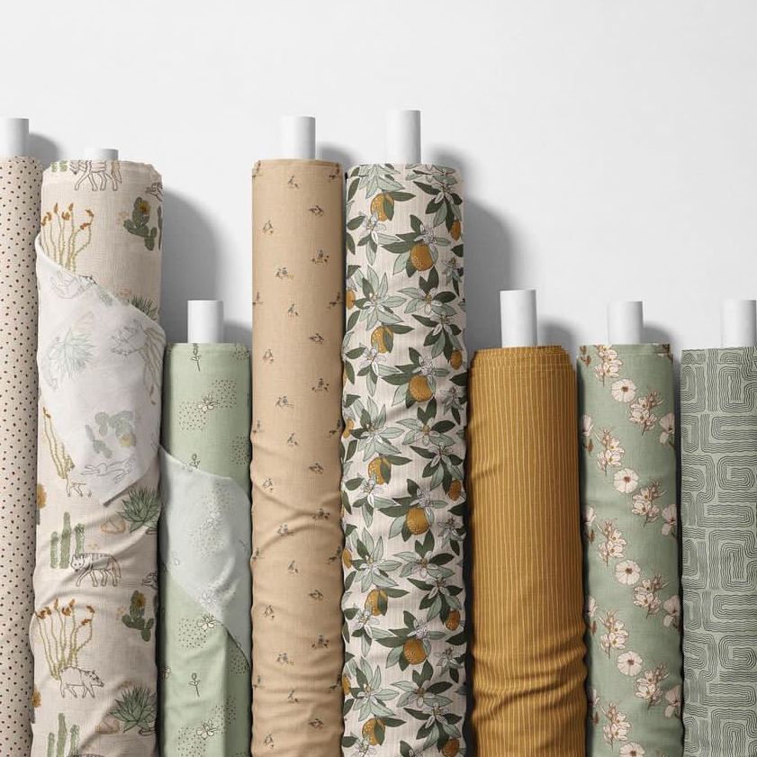 Fabric rolls mockup featuring eight upright rolls with various botanical and geometric patterns in earthy and green tones.