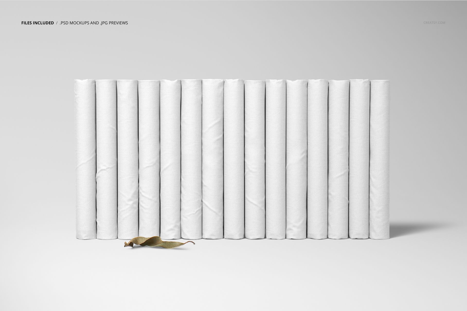 Folded fabrics mockup showing fifteen vertical white textile rolls lined up, with a dried leaf placed in front.