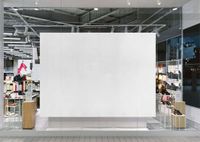 Front view of a large rectangular light box display mockup in a modern shopping mall storefront with glass walls.