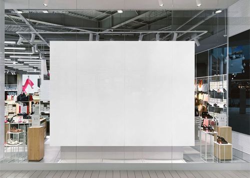 Front view of a large rectangular light box display mockup in a modern shopping mall storefront with glass walls.
