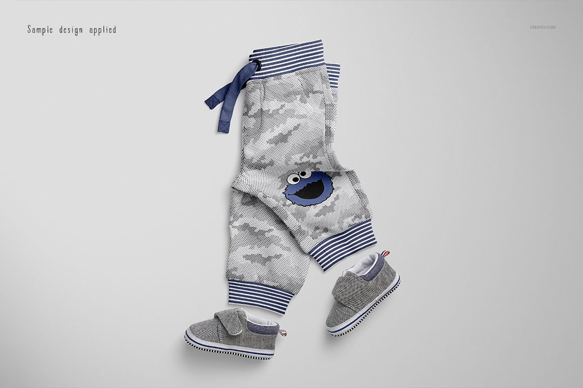 Baby sweatpants mockup featuring gray camouflage pattern, blue striped waistband, and cartoon face detail, top view.