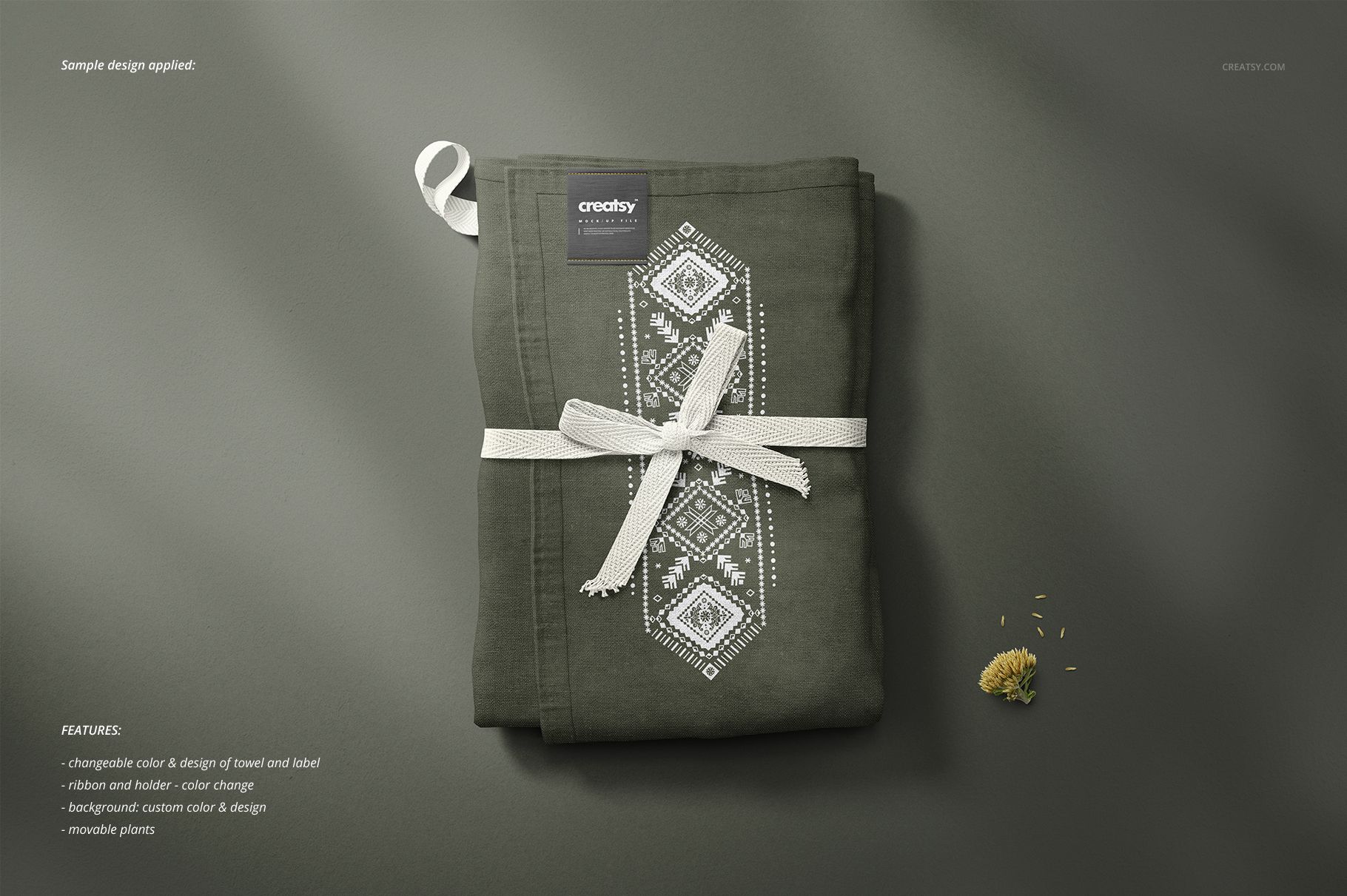 Folded kitchen towel mockup in dark green color with white geometric pattern, tied with a ribbon, top view on gray surface.