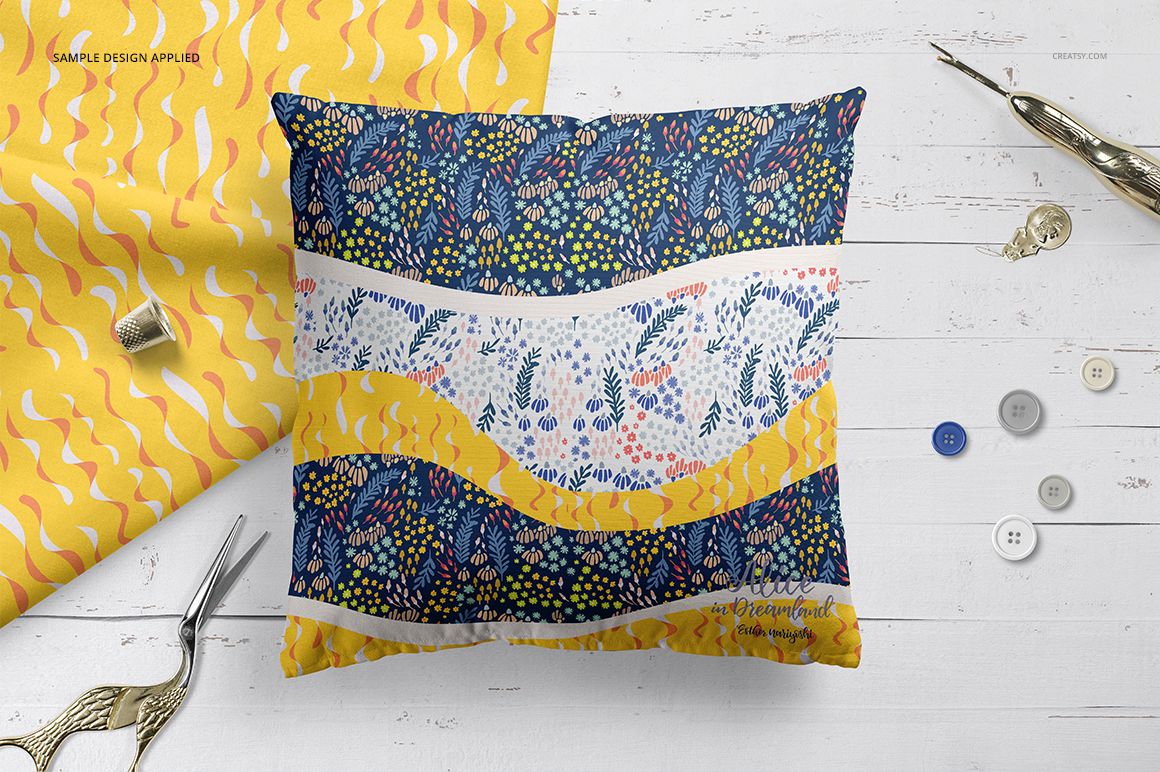 PSD mockup of a square pillow with colorful abstract patterns, surrounded by buttons and sewing props on a wooden background.