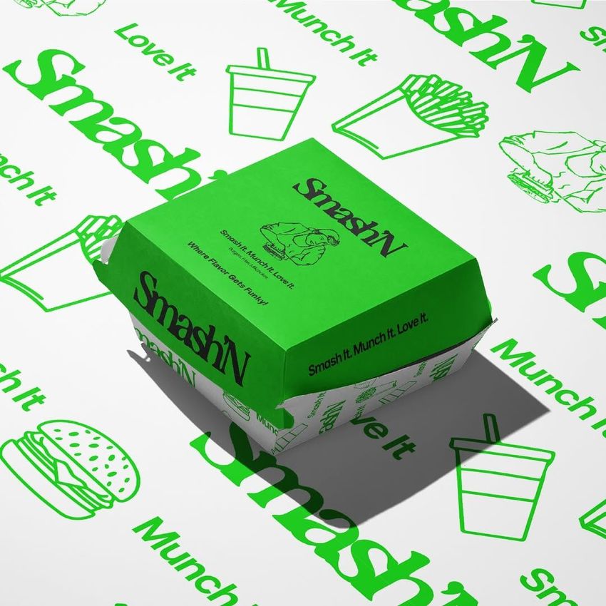 Burger box packaging mockup with a bright green lid featuring bold text and an illustrated burger, surrounded by matching patterned paper.