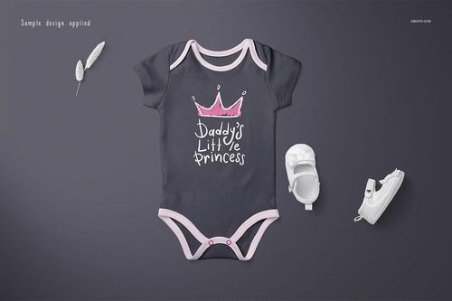 PSD mockup of a short-sleeve baby onesie in dark gray with pink edges, shown with a crown design and shoes nearby.