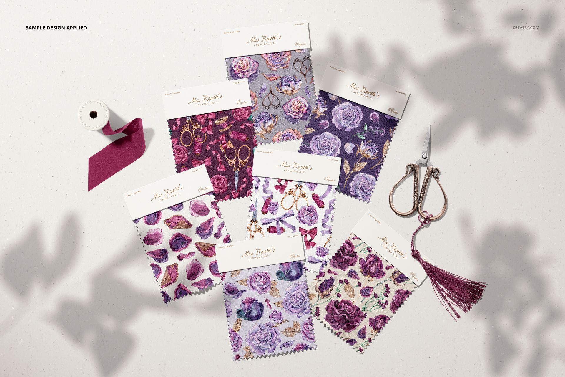 Fabric swatches mockup featuring various purple and pink patterns, shown from a top view with scissors and ribbon nearby.