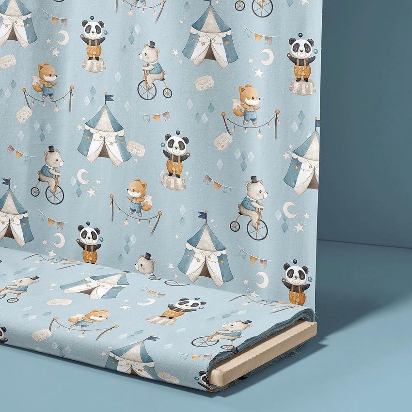 Fabric bolt mockup featuring a whimsical circus-themed pattern with illustrated animals, tents, and stars on a light blue background.