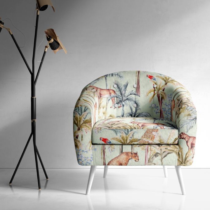 Interior scene mockup showing a patterned armchair with tropical animal and plant motifs, placed beside a modern floor lamp on a light floor.