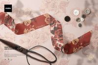 PSD mockup showing a wide cotton ribbon with red and beige flowers, accompanied by sewing tools on a soft fabric base.